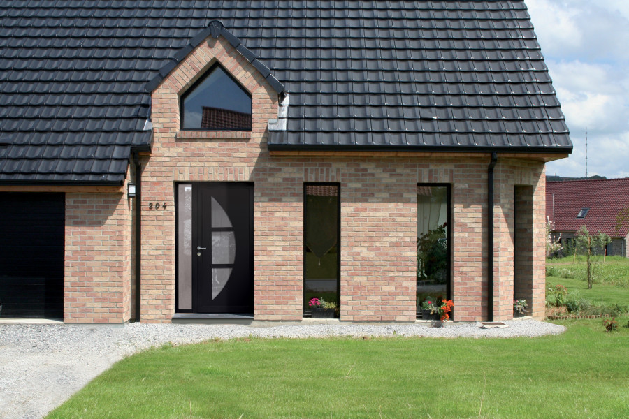 Porte d'entrée aluminium COUCY - Visuel d'ambiance Maison en brique vue de l'extérieur avec porte d'entrée foncée composée de parties vitrées